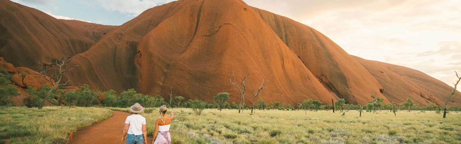 Two young woman walking towards Uluru - Image Mitchell Cox